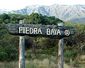 Cartel de piedra y madera en el acceso a Piedra Baya